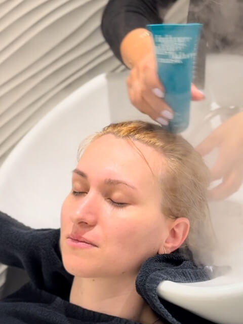 Lana is getting a hair cream applied on her hair