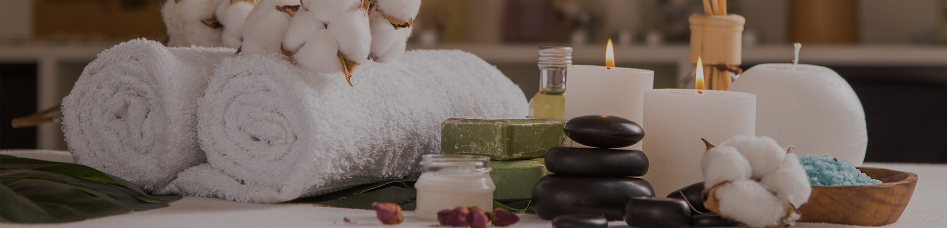 Spa setting with rolled towels, candles, stones, and bath salts.