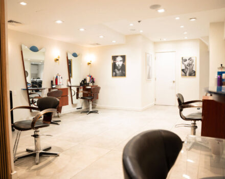 A room in a beauty salon filled with chairs, mirrors, and beauty products.