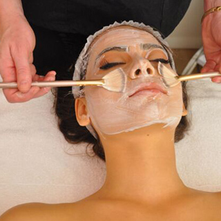 A woman receiving a facial treatment, her face covered with a soothing mask, in a serene spa environment.