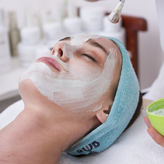 A woman receiving a facial treatment at a serene spa, surrounded by calming decor and soft lighting.